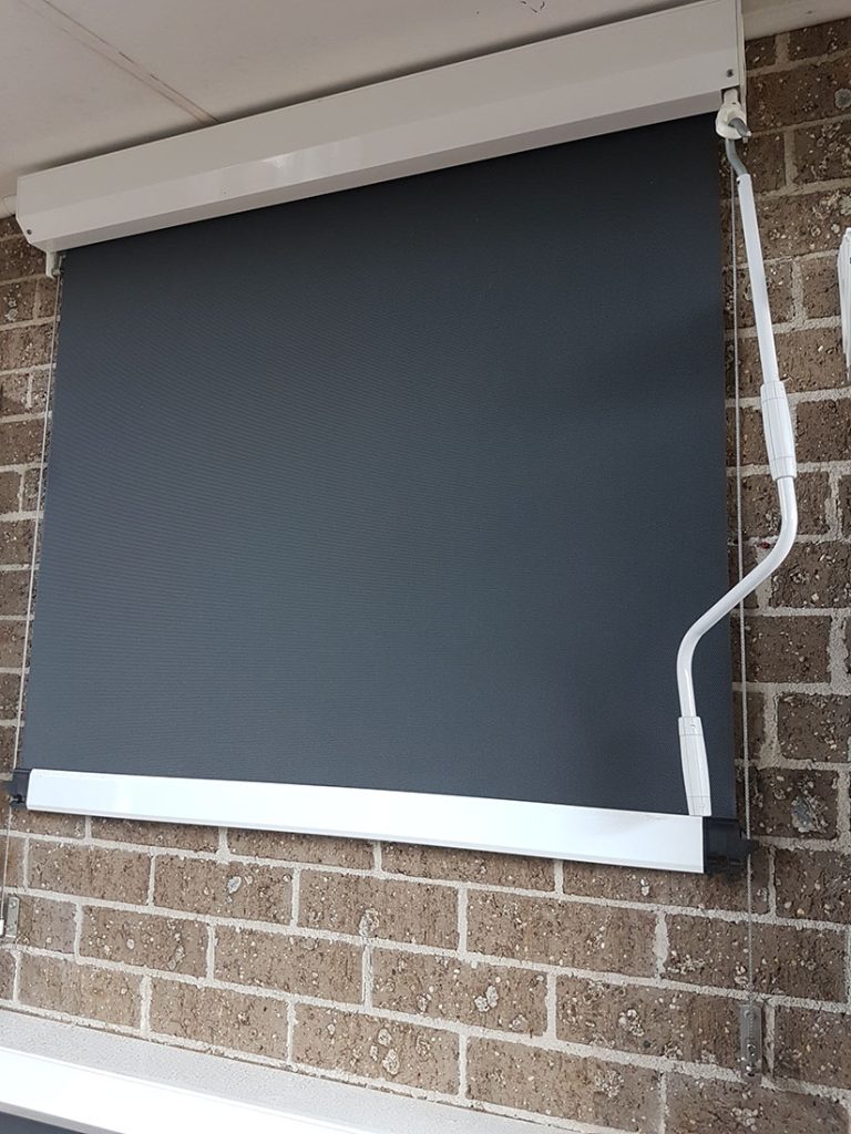 Charcoal outdoor blind on a brick window with side channel