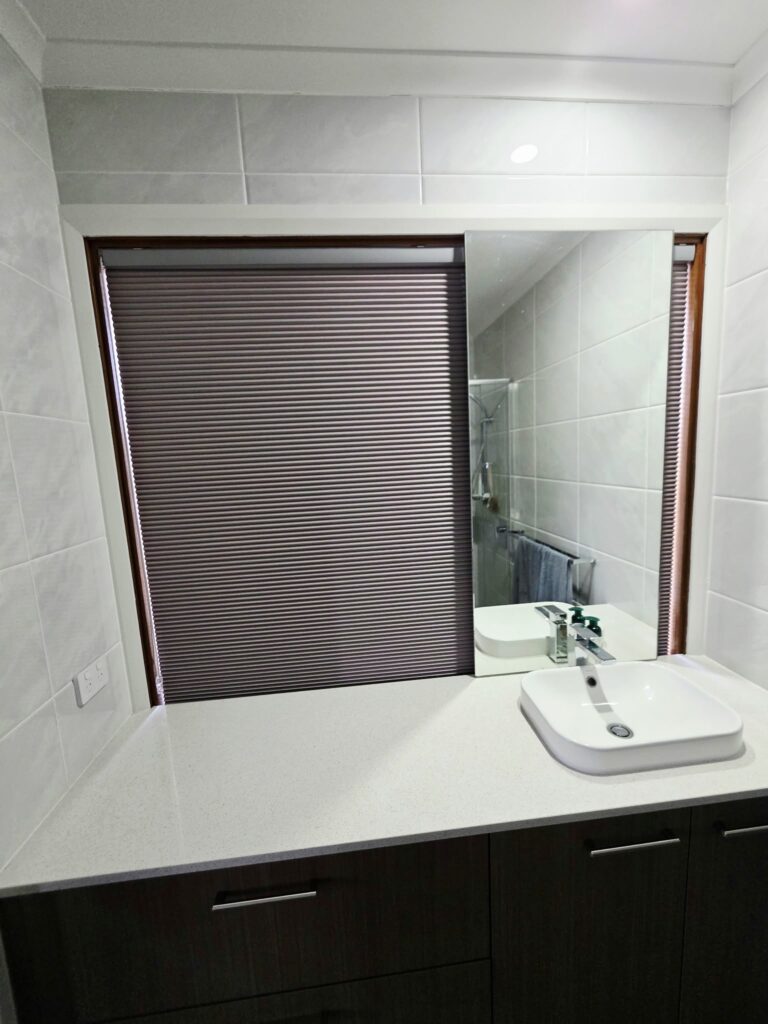 Honeycomb blind on a bathroom window above the vanity