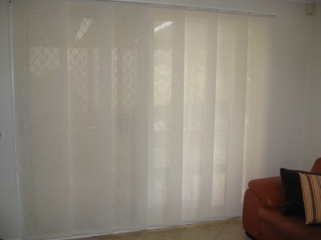 Cream light filtering panel glide blinds across a sliding door