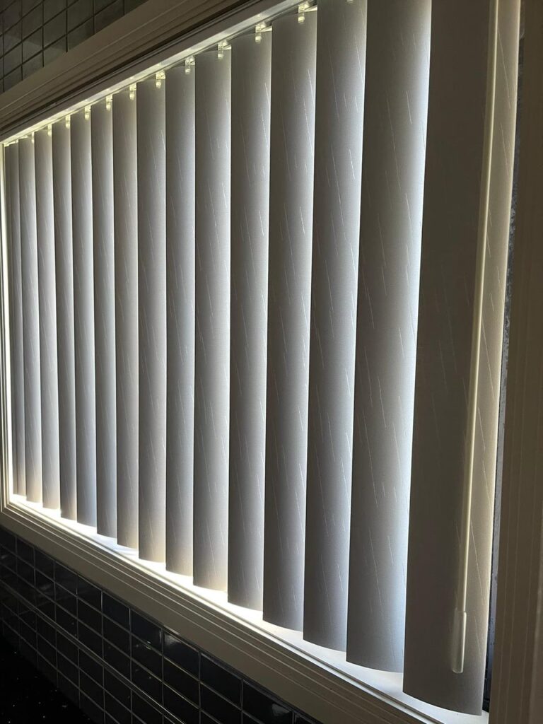 Close-up of textured PVC vertical blind slats on a kitchen window