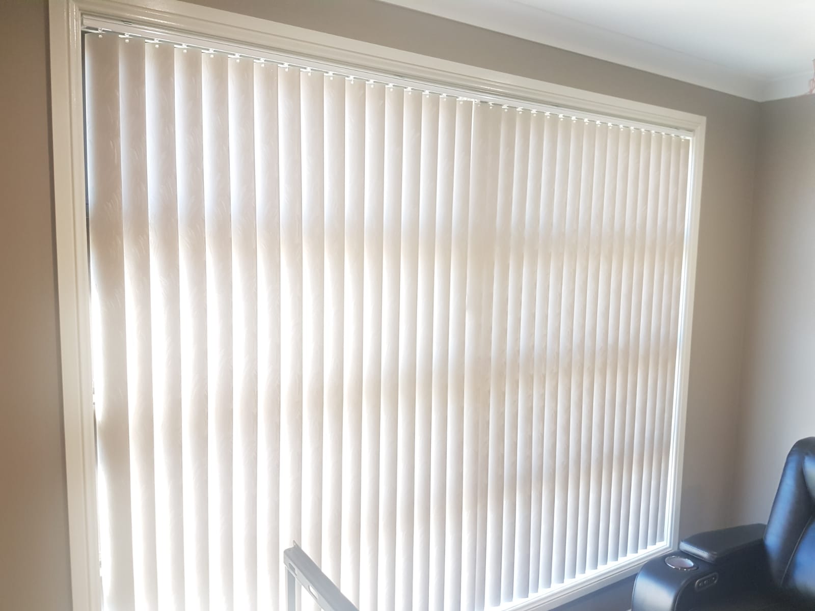 Patterned white PVC vertical blinds on a large window