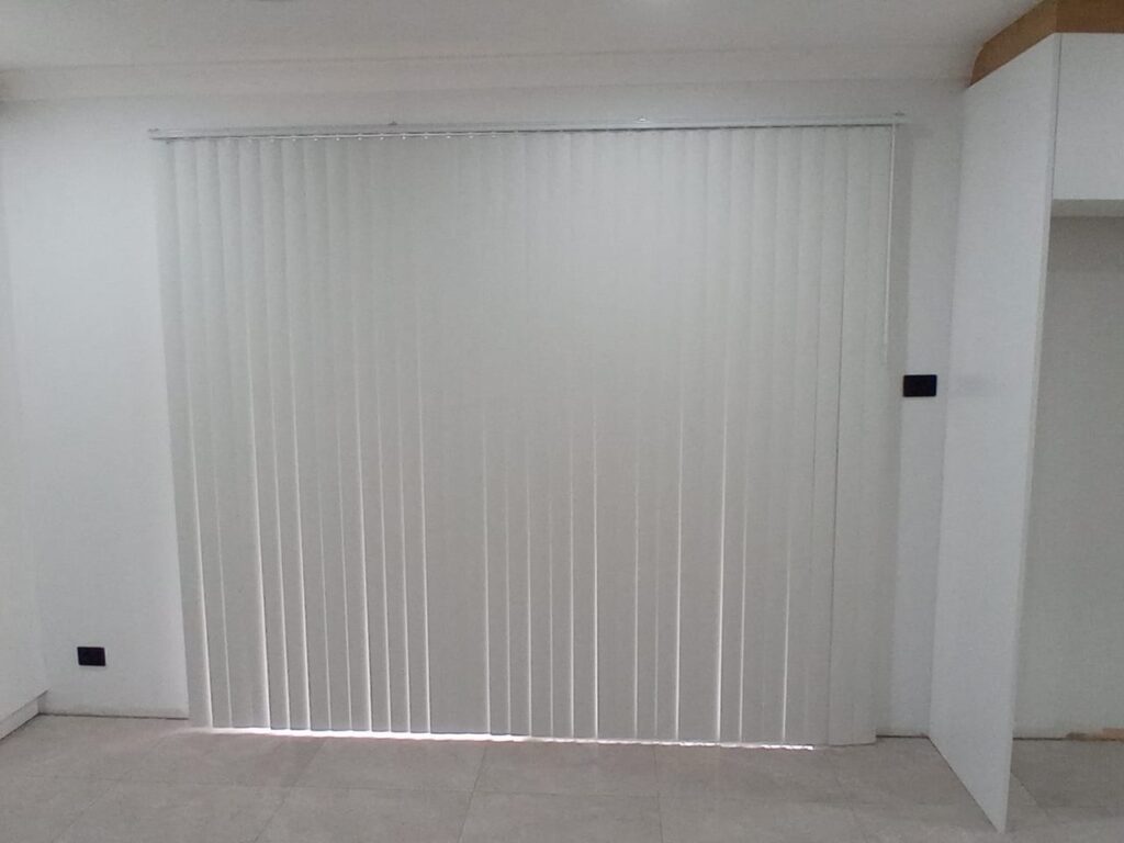 White PVC vertical blinds closed across a sliding door