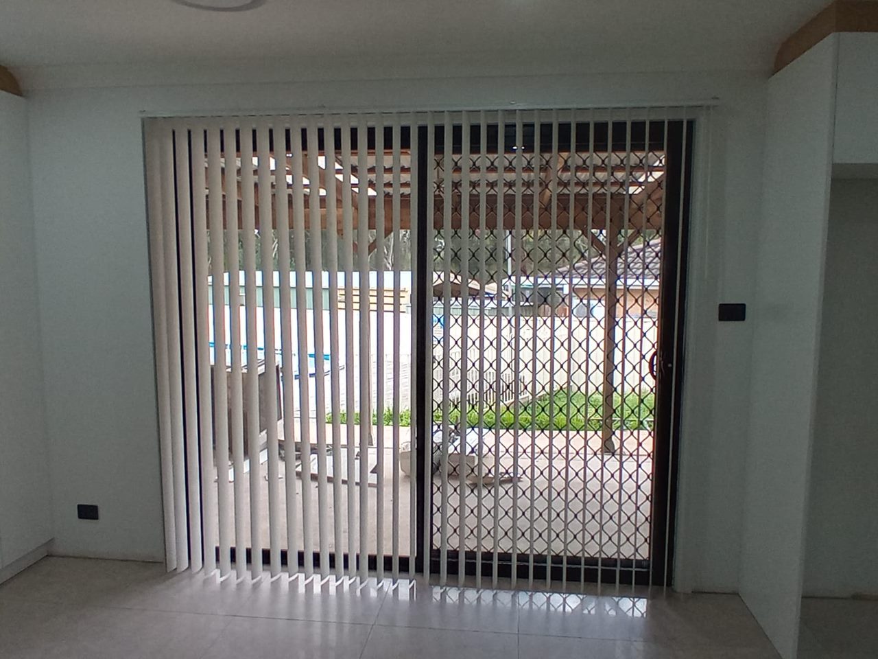 White PVC vertical blinds tilted open on a sliding patio door